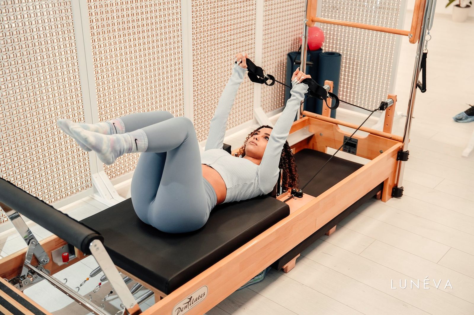 Nő pilates reformeren fekve, meleg fakeretes gépen